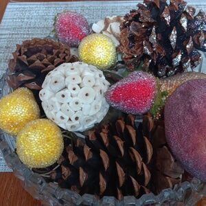 Faux fruit, pinecones,and nesting balls to display in a bowl or table accent .